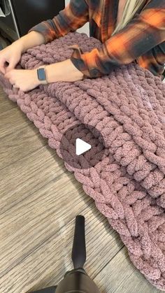 a woman is making a crocheted blanket out of yarn