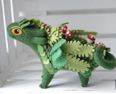 a small green stuffed animal with leaves and berries on it's back