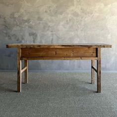 a wooden table sitting on top of a carpeted floor next to a gray wall