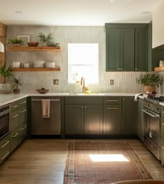 a kitchen with green cabinets and white walls, an area rug on the floor in front of the stove