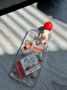 a cell phone case with a strawberry on top and some candy in the back ground