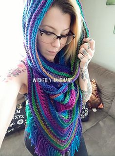 a woman with glasses wearing a multicolored knitted scarf and holding a cell phone up to her ear