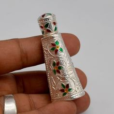 a person holding a small silver lighter in their left hand and the lighter is decorated with flowers