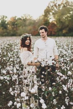 a man and woman standing in a field of cotton