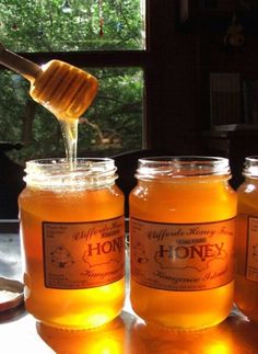 honey is being poured into jars on a table