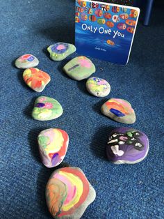 rocks with different colors and shapes are on the floor next to a children's book