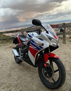 a red, white and blue motorcycle parked on top of a hill