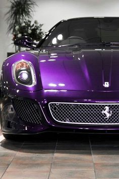 a purple sports car parked in a showroom with its hood up and lights on