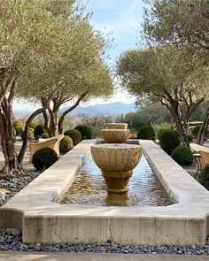 an outdoor fountain surrounded by trees and benches