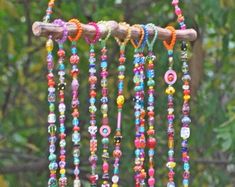 a wind chime hanging from a tree branch with beads and other things on it