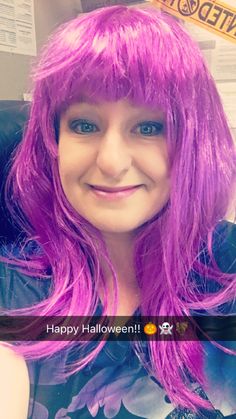 a woman with pink hair is smiling at the camera while wearing a black shirt and purple wig