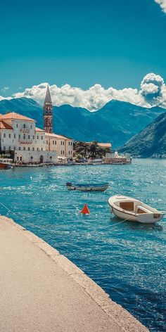 boats floating in the water near buildings and mountains