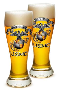 two beer glasses sitting next to each other on top of a white surface with an eagle emblem