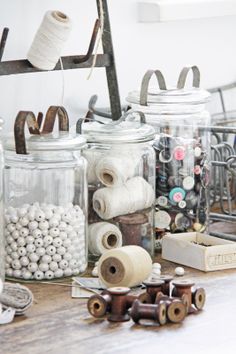 several jars filled with different types of thread and spools on top of a table