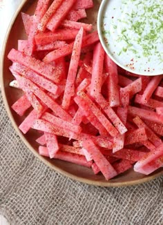 watermelon sticks and dip in a bowl on a cloth with spoons next to it