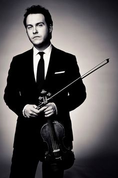 a man in a suit and tie holding a violin