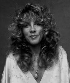 a black and white photo of a woman with long curly hair wearing a dress shirt