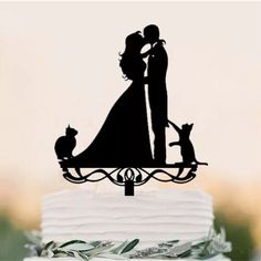 a wedding cake topper with a bride and groom holding their dog on the side