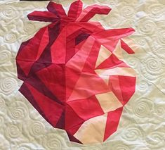 a piece of paper that has been made into a heart on a quilted surface