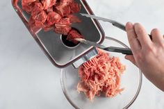 someone is cutting meat into small pieces on a glass plate with a large pair of scissors