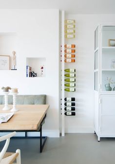 a dining room with a table and chairs next to a wine rack on the wall