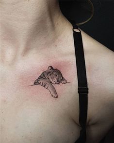 a woman's chest with a tattoo of a cat laying on top of it