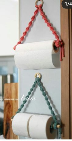 two rolls of toilet paper hanging on a wall next to a roll of yarn and a pair of scissors