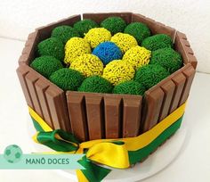 a chocolate cake with green and yellow decorations in a wooden box on a white plate