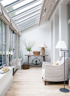 a living room filled with lots of furniture next to a tall white wall covered in windows