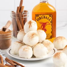 a plate filled with hot dogs covered in powdered sugar next to cinnamon sticks and a bottle of fireball