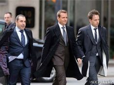 three men in suits walking down the street