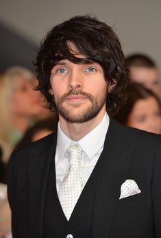 a man wearing a suit and tie with people in the background