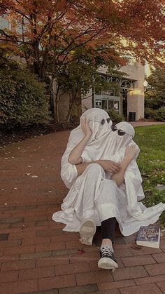 a person sitting on top of a white cloth covered bench in front of a tree