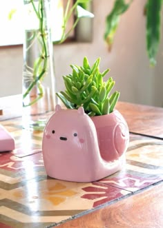 a pink ceramic animal planter with succulents in it on a table