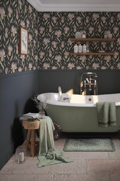 a bath tub sitting next to a wooden stool in a bathroom with wall paper on the walls