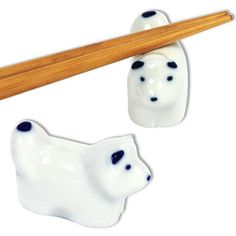 two white bears with black spots on them and a wooden chopstick in the shape of a bear