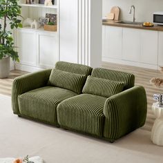 a green couch sitting in the middle of a living room next to a white rug