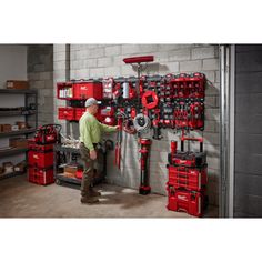 a man working on a wall mounted tool rack in a garage with tools and equipment