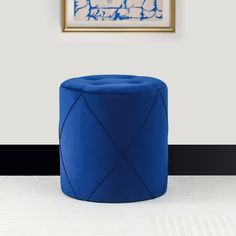 a blue stool sitting on top of a white floor next to a framed painting in a living room