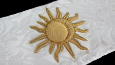 a gold embroidered sun on white fabric