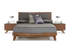 a bed with two nightstands next to it and a gray pillow on the top