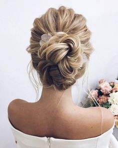 the back of a woman's head, with flowers in the background and her hair styled into a low bun