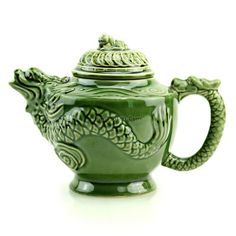 a green teapot with a dragon design on the front and sides, sitting on a white surface