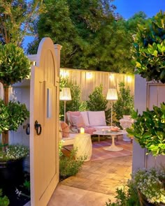 an outdoor living area is lit up with lights and greenery on either side of the door