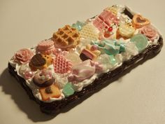 a close up of a cell phone covered in candies and waffles on a table