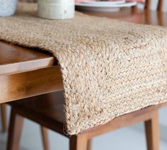 a close up of a wooden table with a cloth on top of it and plates in the background