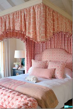 a dog laying on a bed with pink and white bedspread in a bedroom