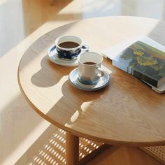 a table with a book, coffee cup and saucer on it