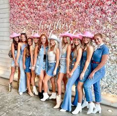 a group of women standing next to each other in front of a wall with flowers