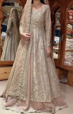 a woman standing in front of a mirror wearing a wedding gown and veil with flowers on it